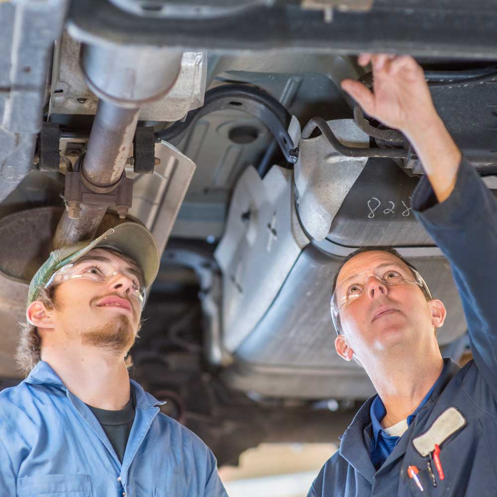 Two people working on a car together.