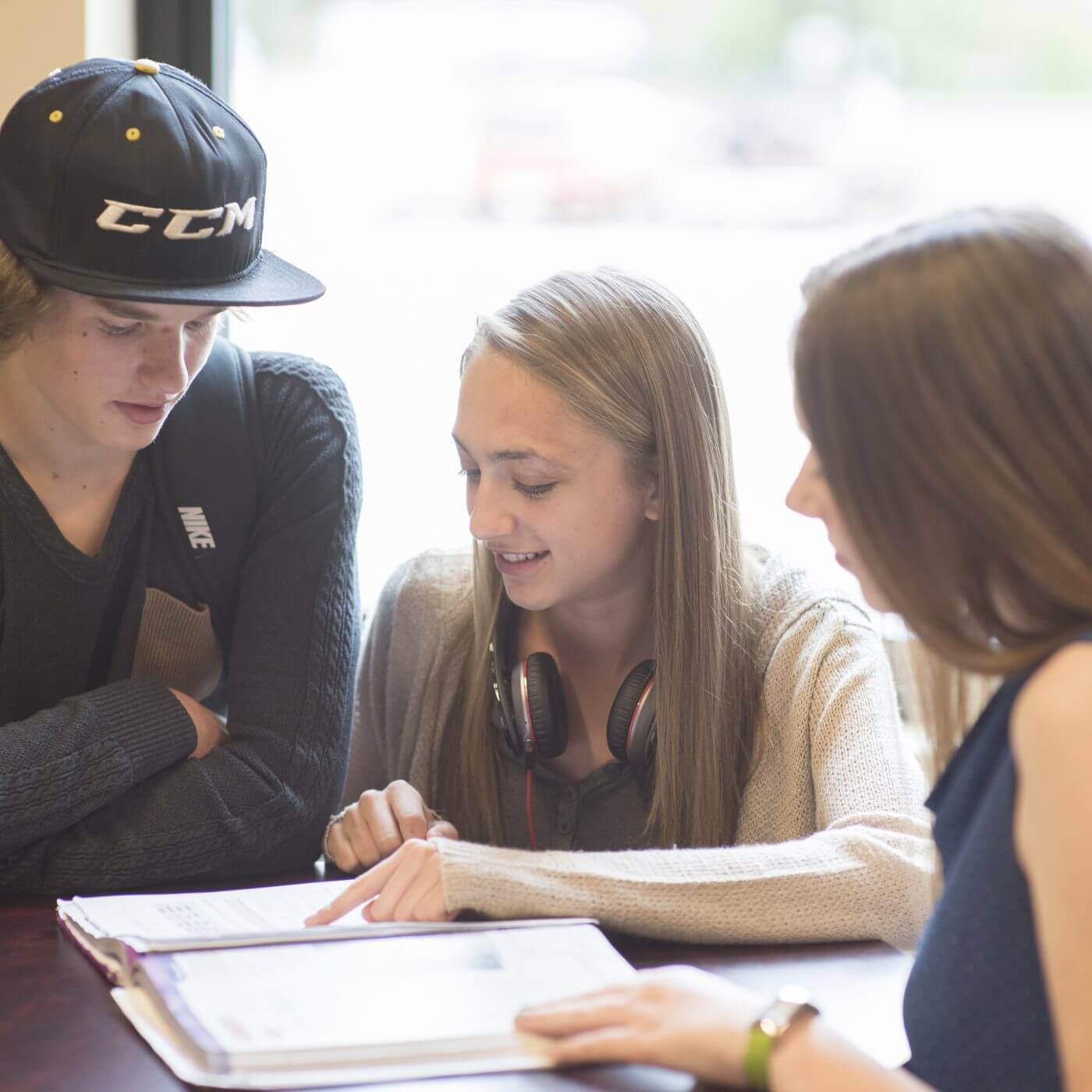 Three students reviewing a textbook together.